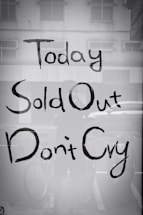A shop window displays text reading 'Today Sold Out Don't Cry' in a casual, hand-painted style. The reflection shows part of a bicycle and some indistinct elements in an urban setting.