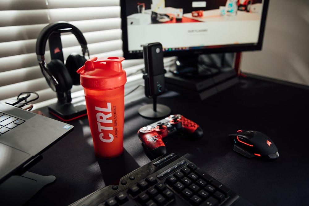 red and black tumbler beside black computer keyboard