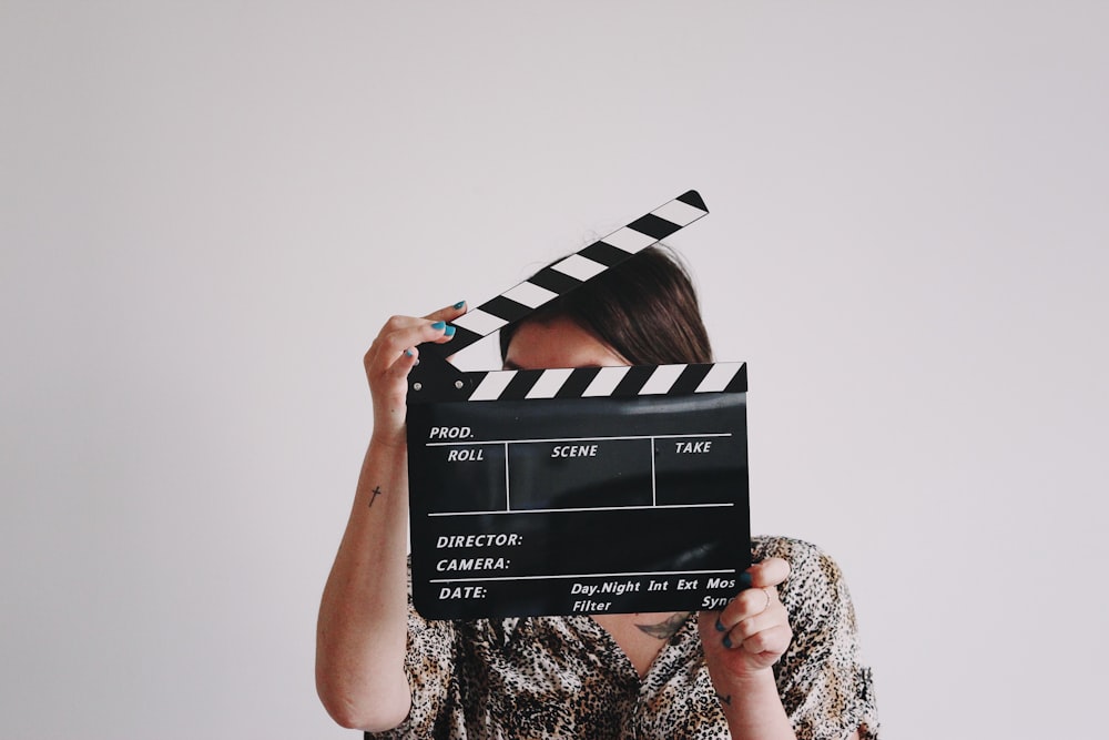 a woman holding a clapper over her face