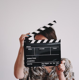 a woman holding a clapper over her face