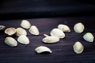 Freshly picked pistachios still in their shells, laid out on a traditional Afghan patterned fabric.