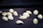 Scattered pistachio nuts are positioned on a dark wooden surface. The nuts appear to be raw and some have half-opened shells.