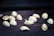 Scattered pistachio nuts are positioned on a dark wooden surface. The nuts appear to be raw and some have half-opened shells.