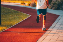 A smiling person jogging in sleek fitness apparel with a scenic park background.