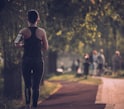 woman in black tank top and black pants walking on sidewalk during daytime