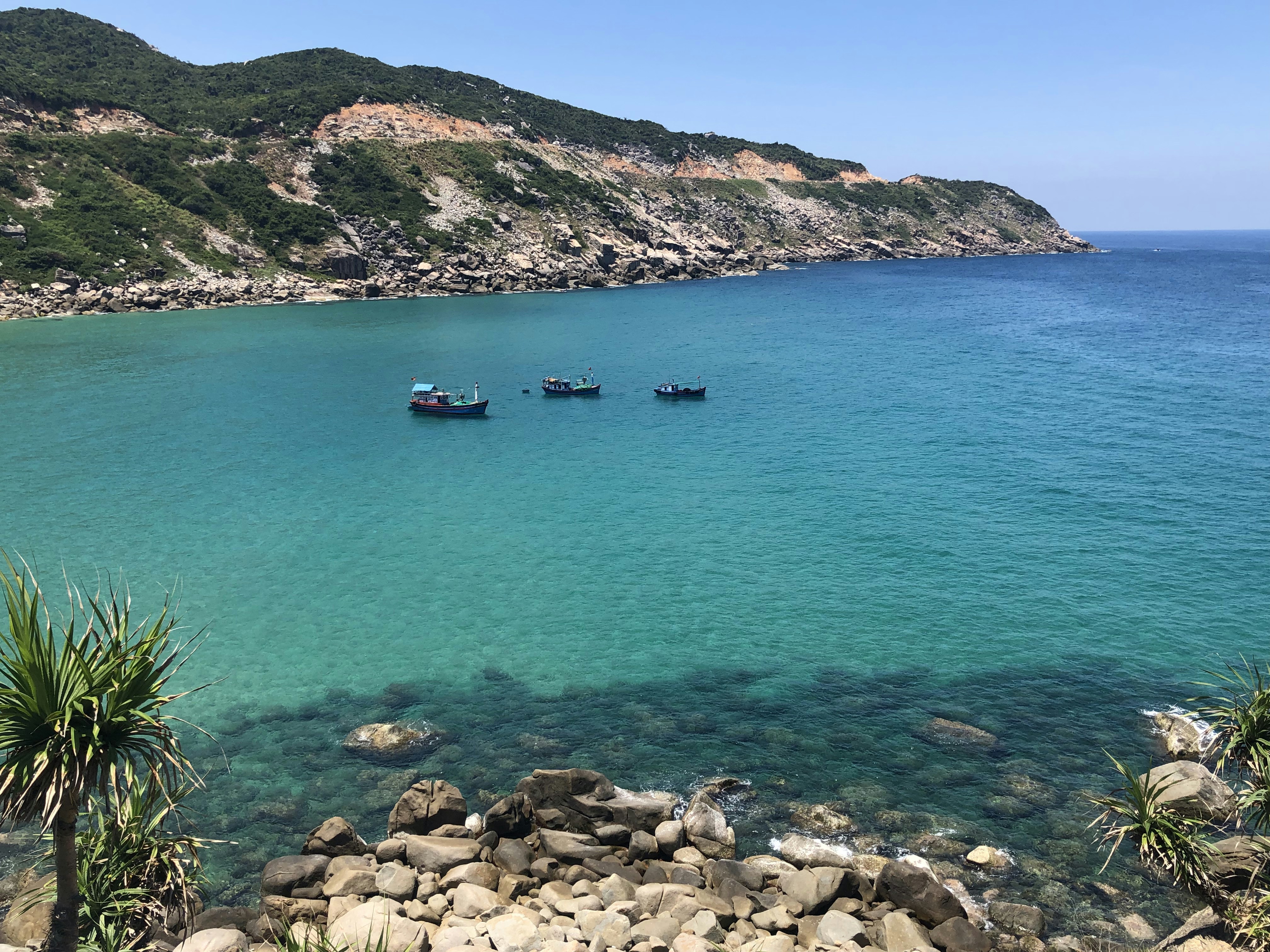 boat on sea near rocky mountain during daytime