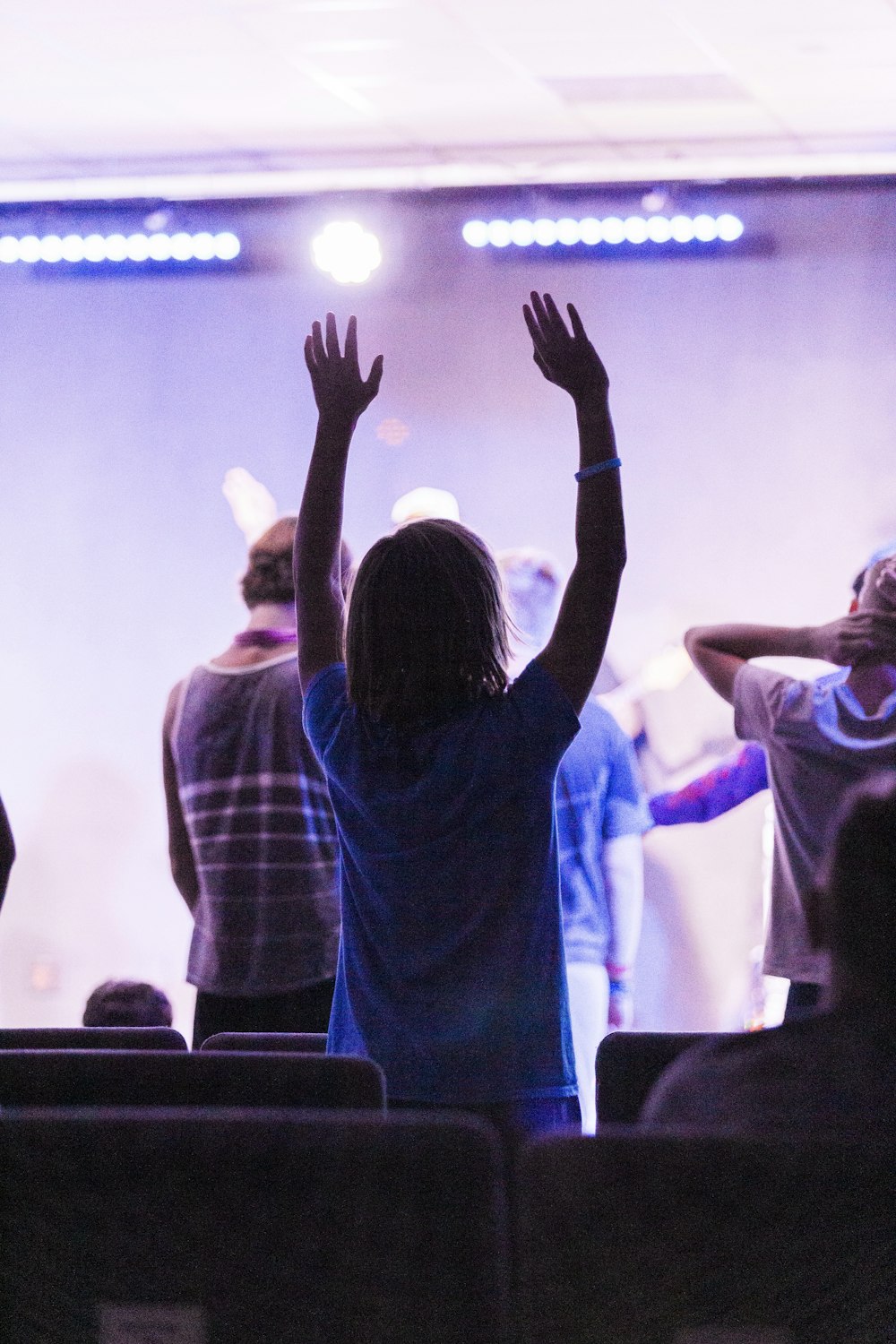 woman in blue dress shirt raising her hands