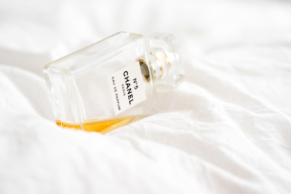 clear glass perfume bottle on white textile