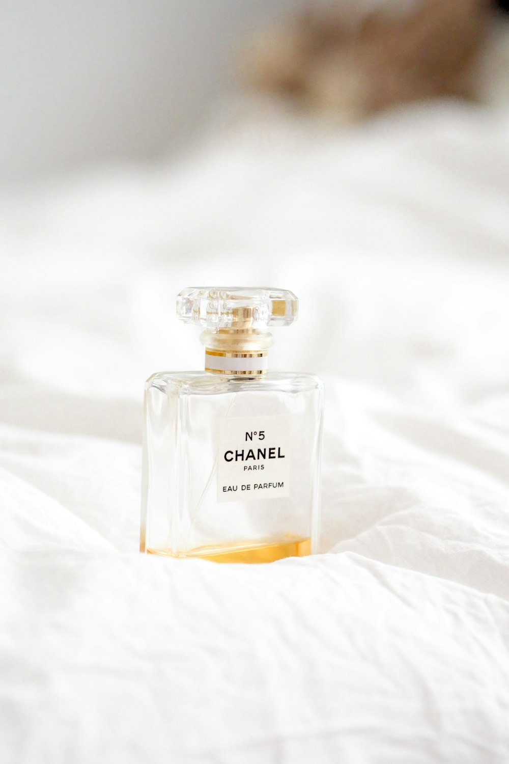 clear glass perfume bottle on white textile