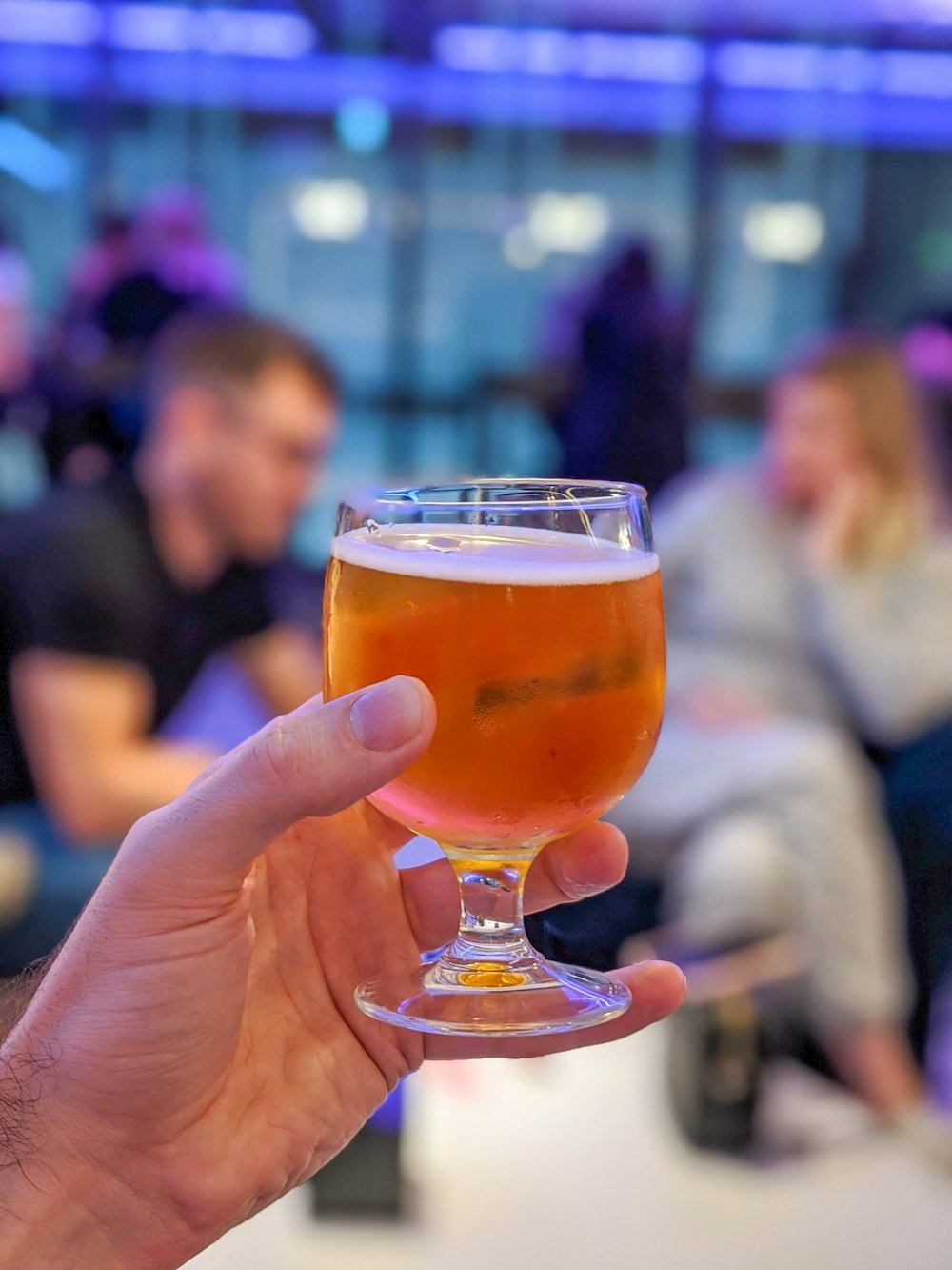 person holding clear drinking glass with brown liquid