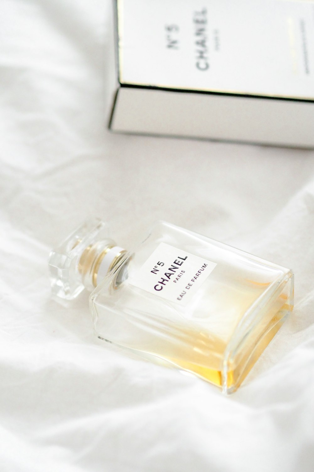 Flacon de parfum en verre transparent sur textile blanc