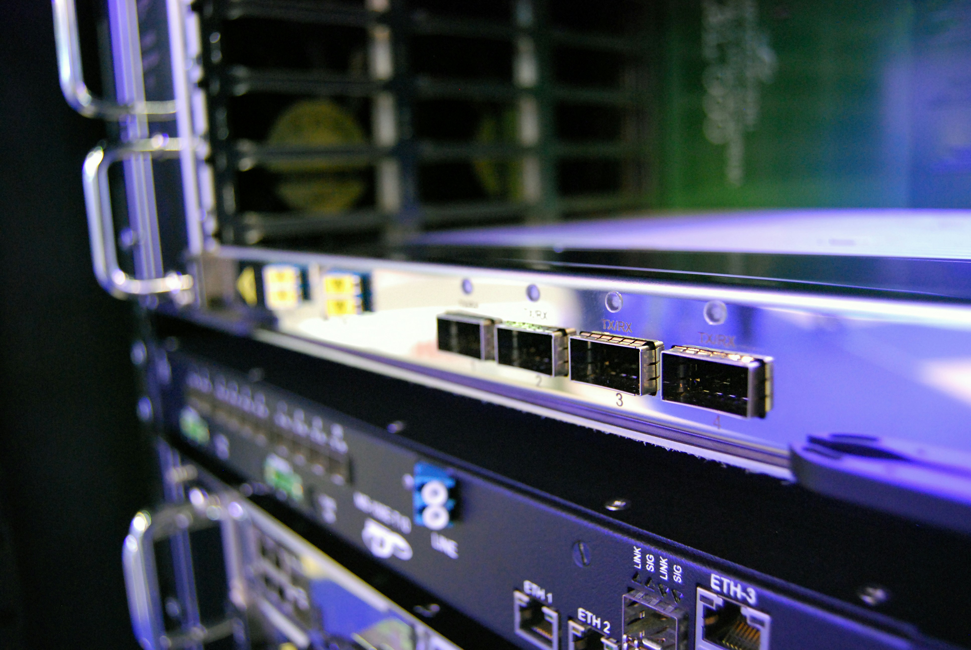 Network switch with blinking blue LED ports in dark server room with cable management