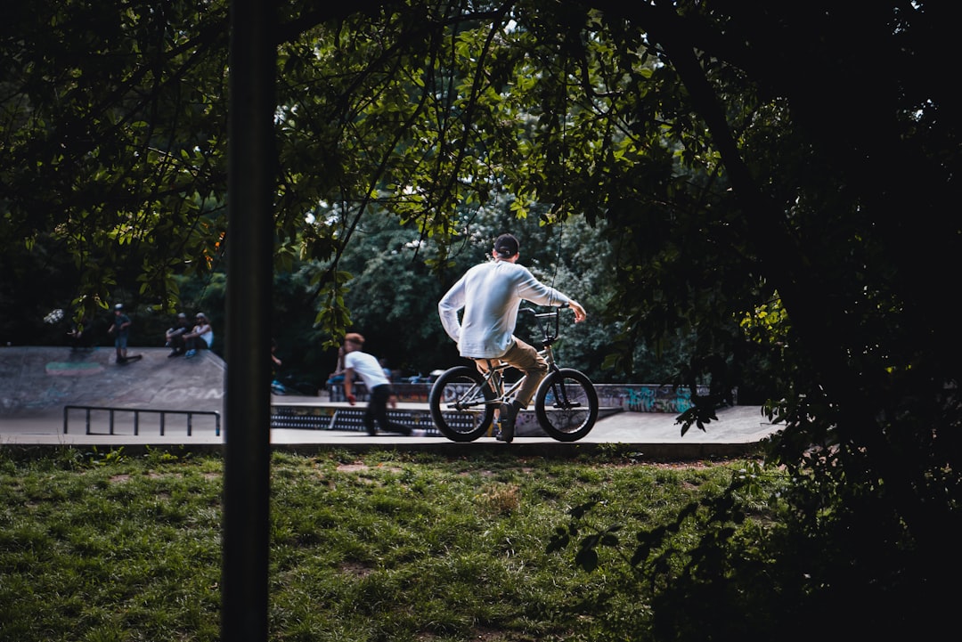 man in white t-shirt riding bicycle on park during daytime