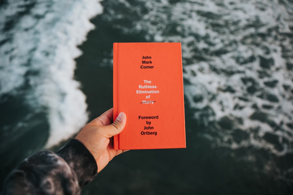 person holding red and white book