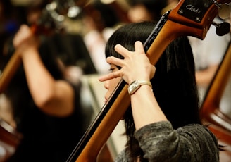 woman in gray long sleeve shirt holding orange and black guitar