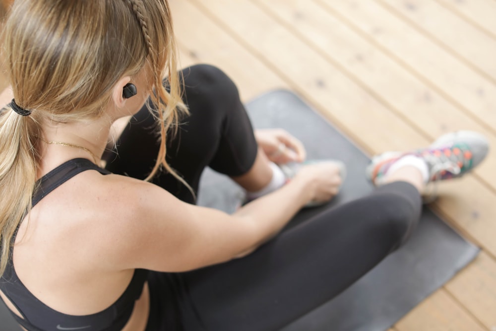 woman in black tank top and black leggings sitting on gray bench