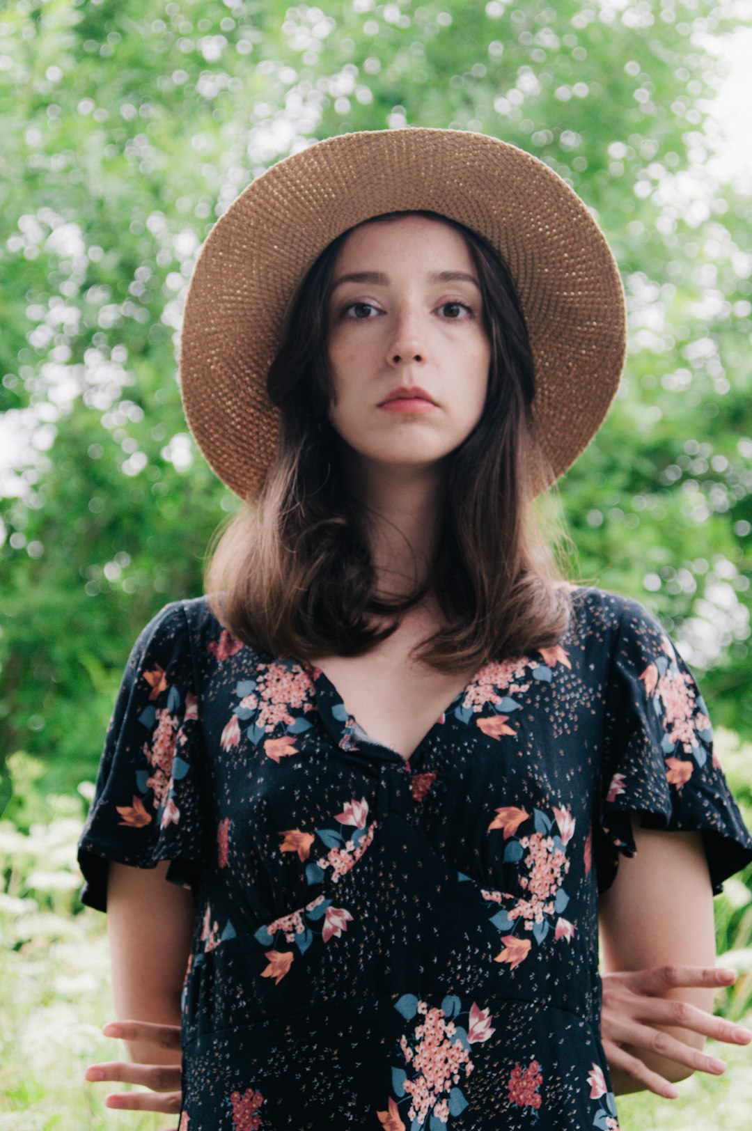 woman in black and white floral shirt wearing brown straw hat