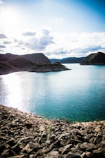 blue lake surrounded by mountains under white clouds and blue sky during daytime
