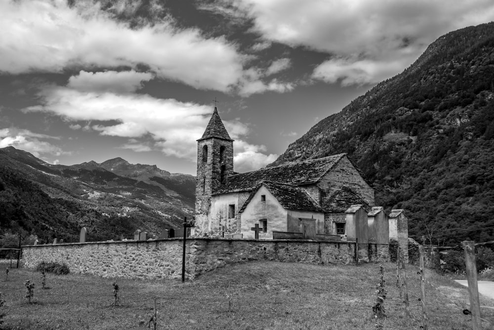grayscale photo of church near mountain