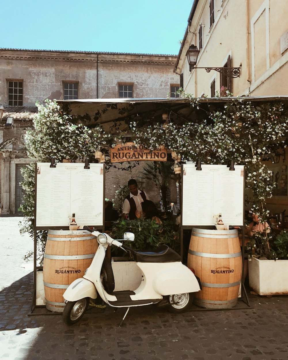 white motor scooter parked beside brown wooden barrels