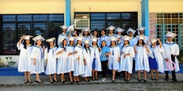 Group of students in white coats smiling outside the institute building.