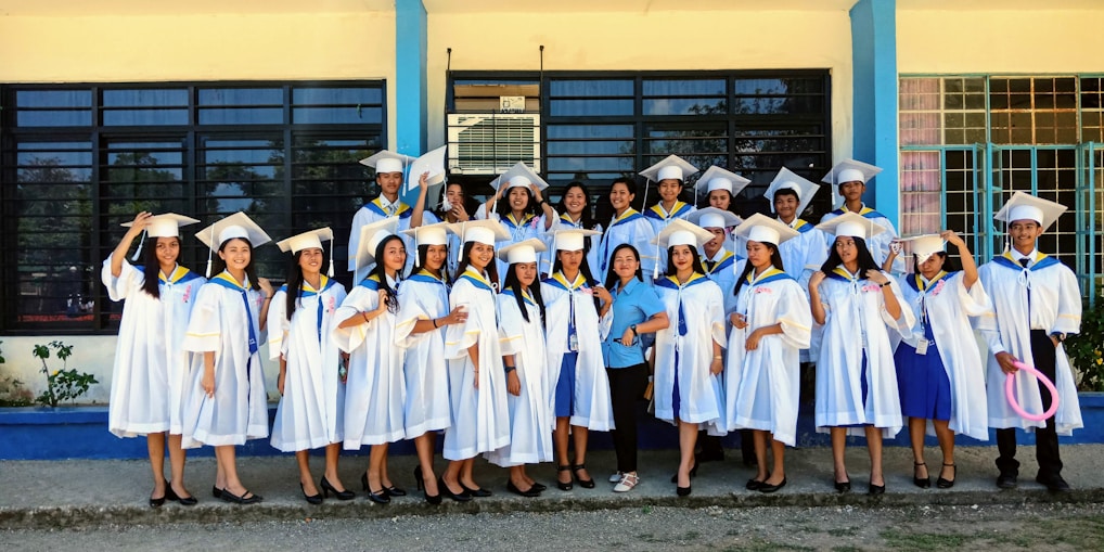 A group of smiling students holding their admission letters outside a university campus.