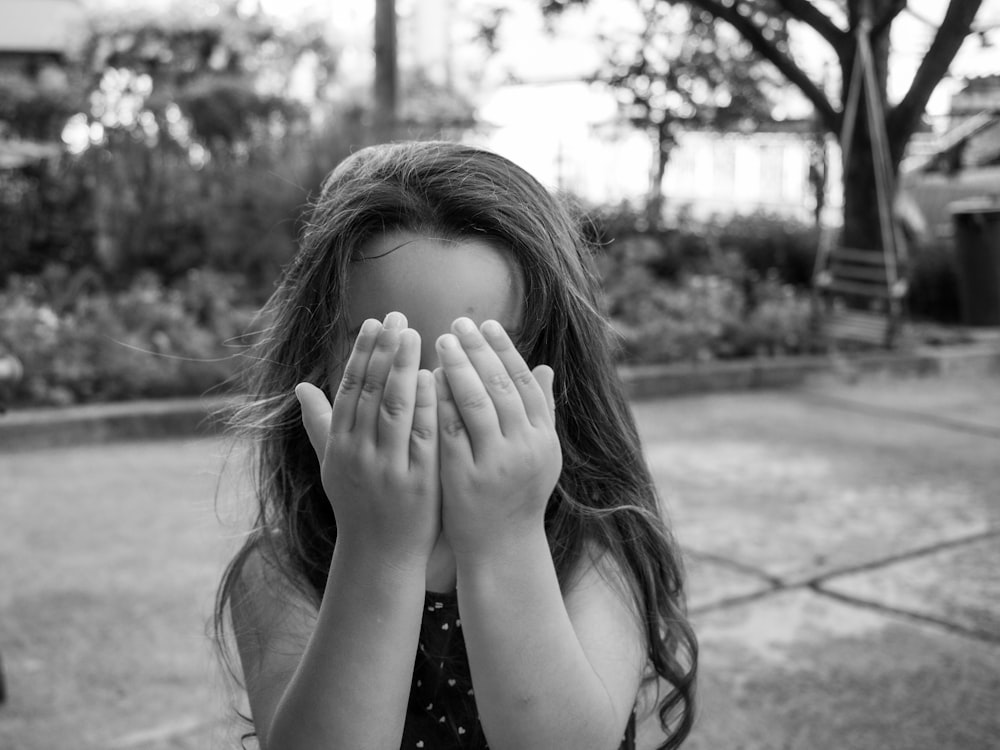 grayscale photo of woman covering her face with her hands