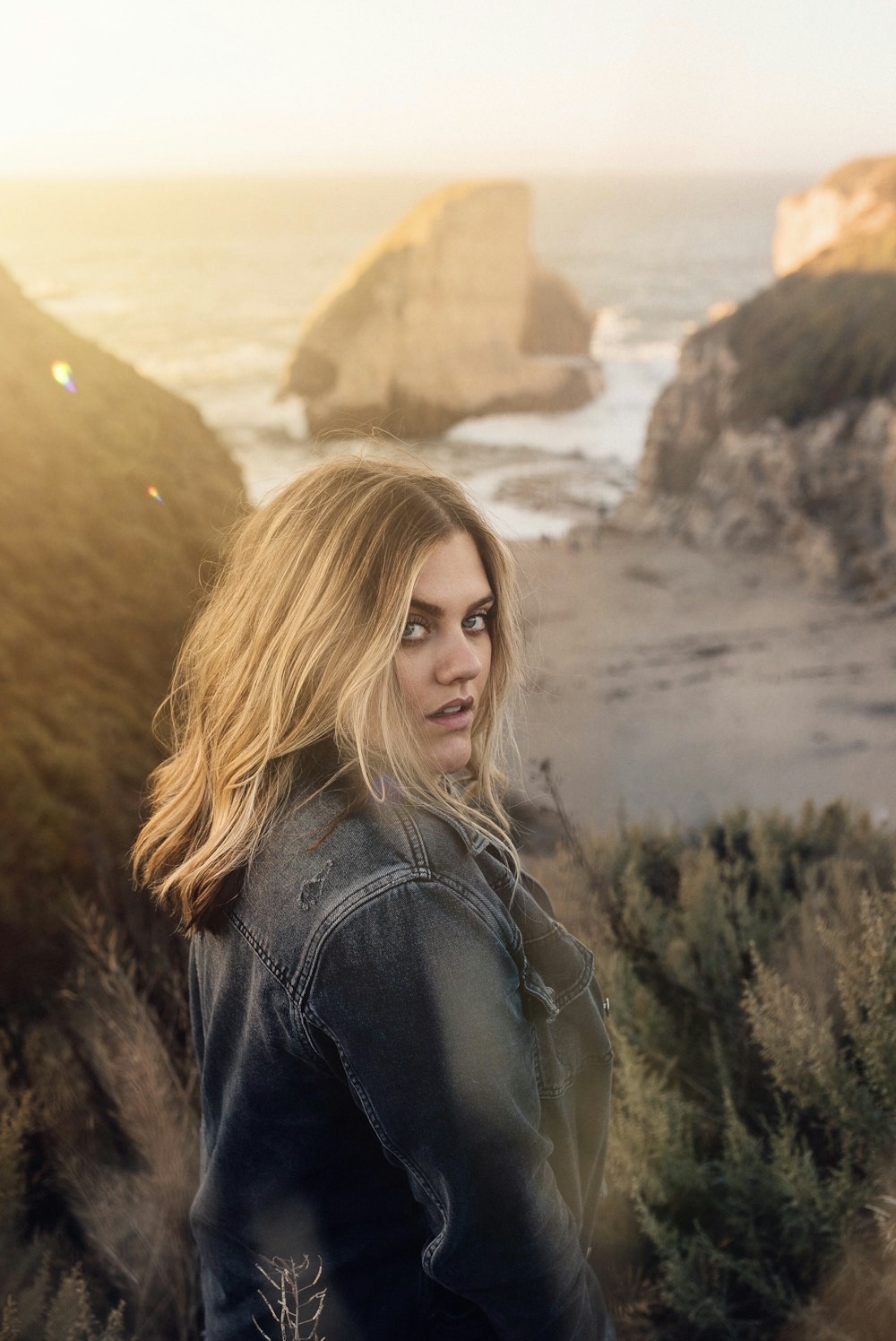 woman in black leather jacket standing near brown rock formation during daytime