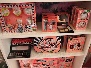 A showcase of cosmetic gift sets arranged on white shelves, featuring a range of products with vibrant retro packaging. The sets include various skincare and beauty items, each labeled with unique design and branding. The packaging has a vintage aesthetic with images and bold fonts.