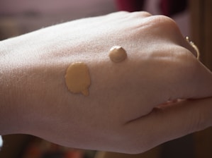 Close-up of a makeup artist applying foundation on a smiling client in a bright studio.