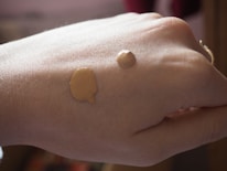 Close-up of a hand applying smooth, glowing foundation on skin.