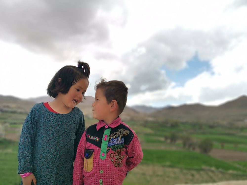 2 boys standing on green grass field during daytime