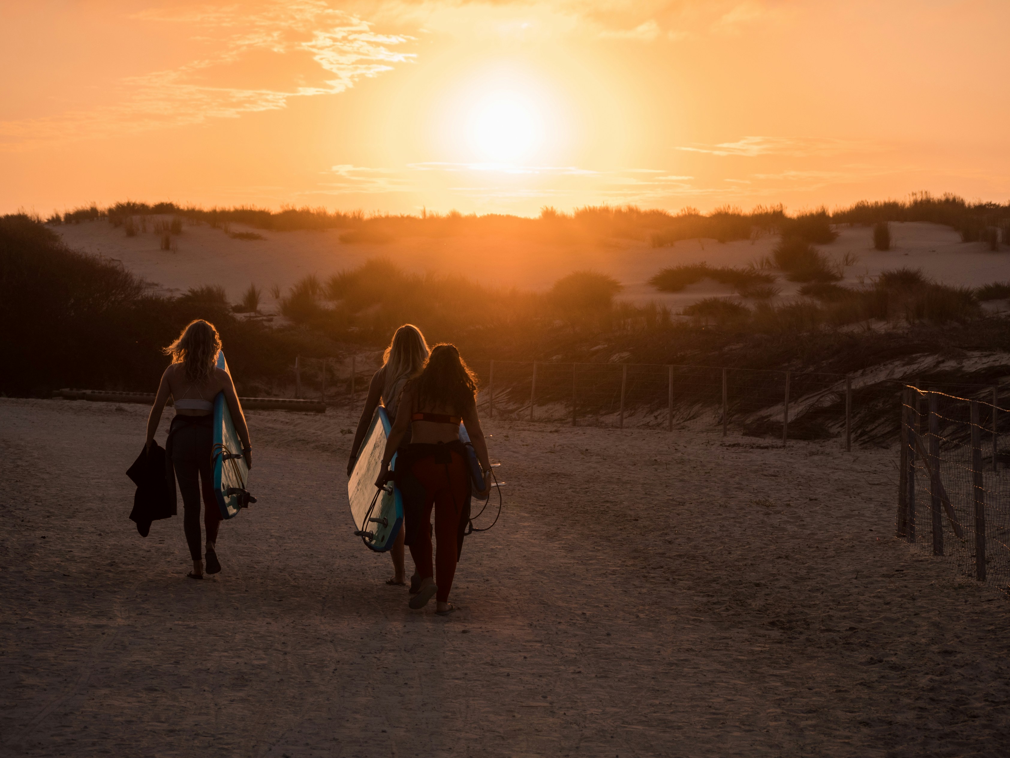 2 women walking on dirt road during sunset