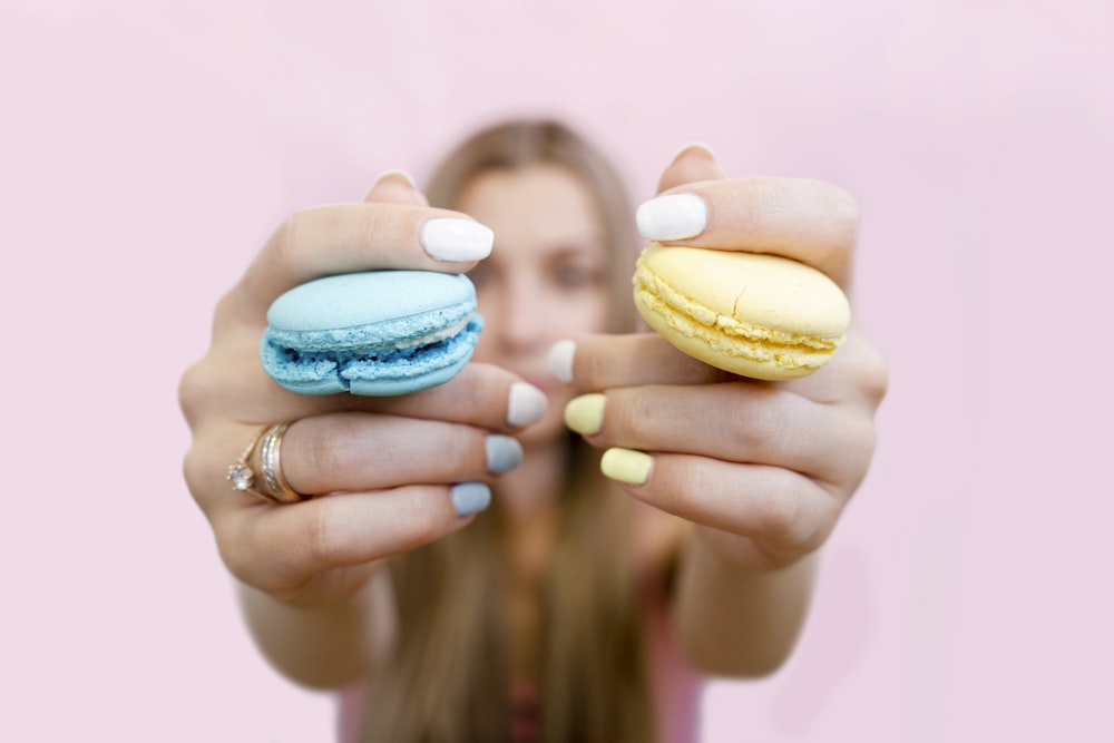 a woman holding two macaroons in front of her face