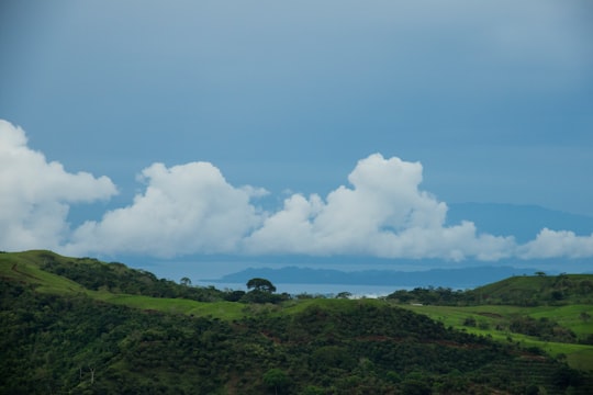 green grass field under white clouds and blue sky during daytime in Guanacaste Province Costa Rica