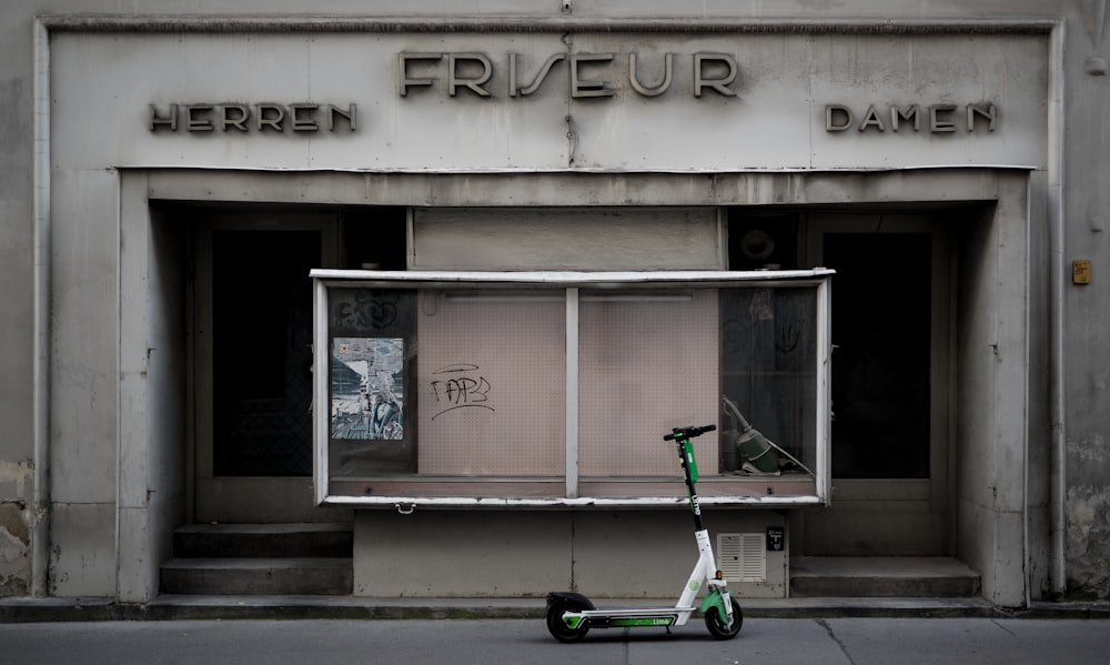 green and black bicycle parked beside the building