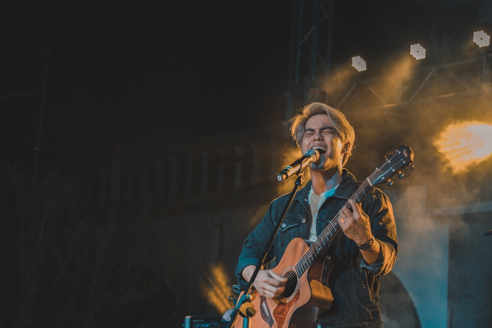 a man holding a guitar while standing on a stage