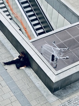 woman in black jacket and black pants lying on gray concrete stairs