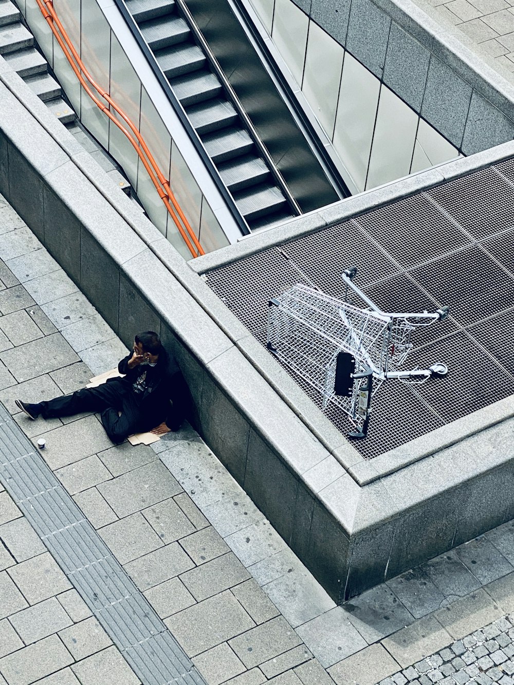 Mujer con chaqueta negra y pantalones negros acostada en escaleras de concreto gris