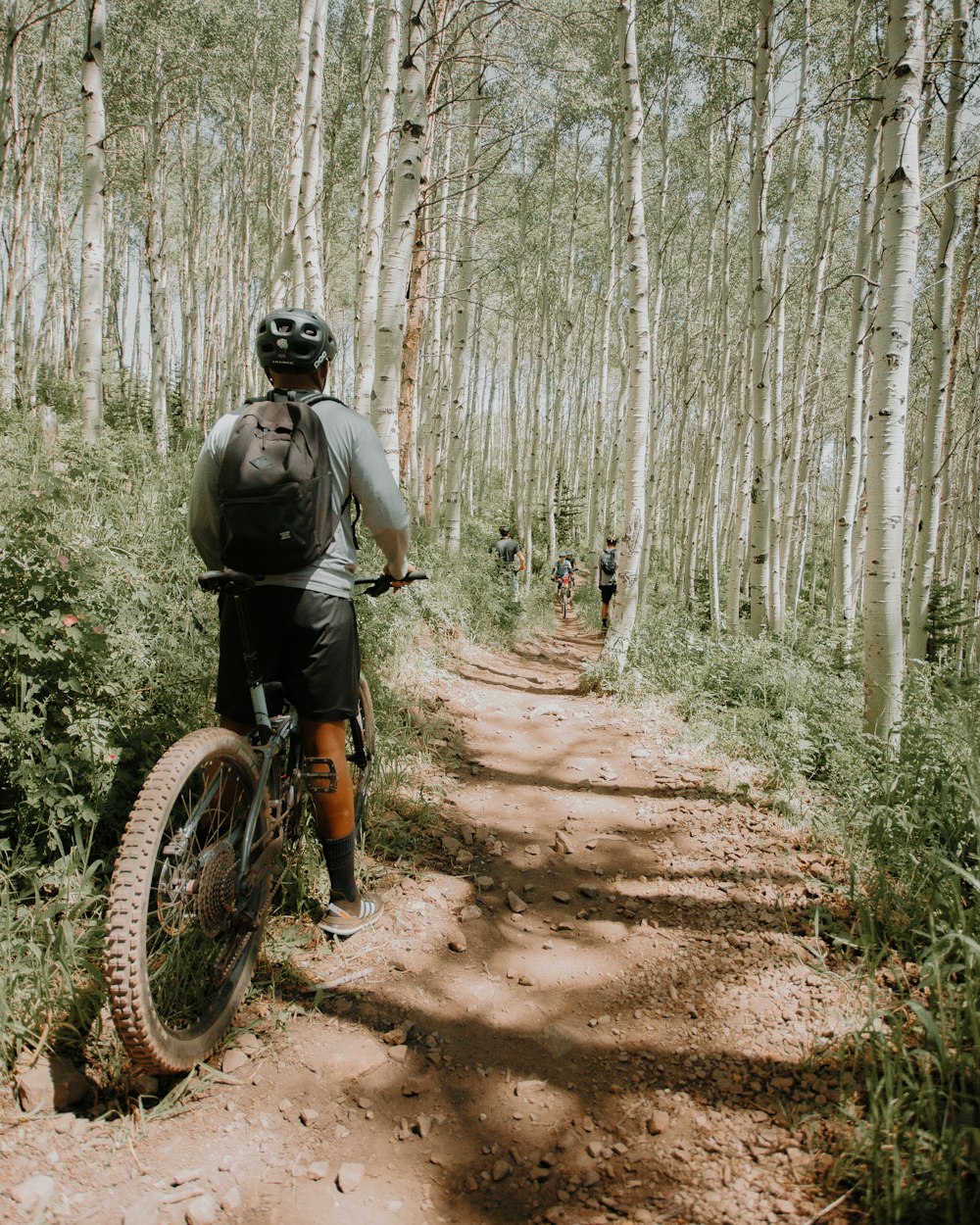 man in green jacket riding bicycle on dirt road during daytime