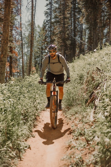 man in black jacket riding bicycle on forest during daytime