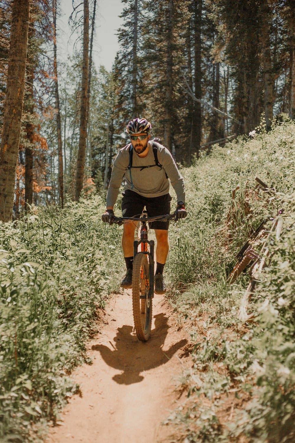 낮 동안 숲에서 자전거를 타는 검은 재킷을 입은 남자