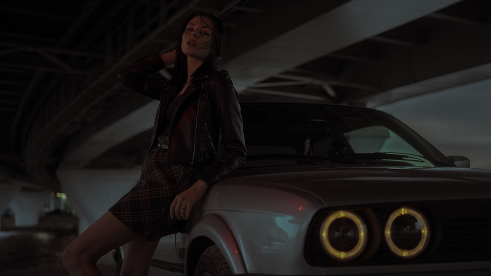 woman in black leather jacket standing beside car