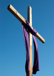 A close-up of a rustic wooden cross against a clear sky.