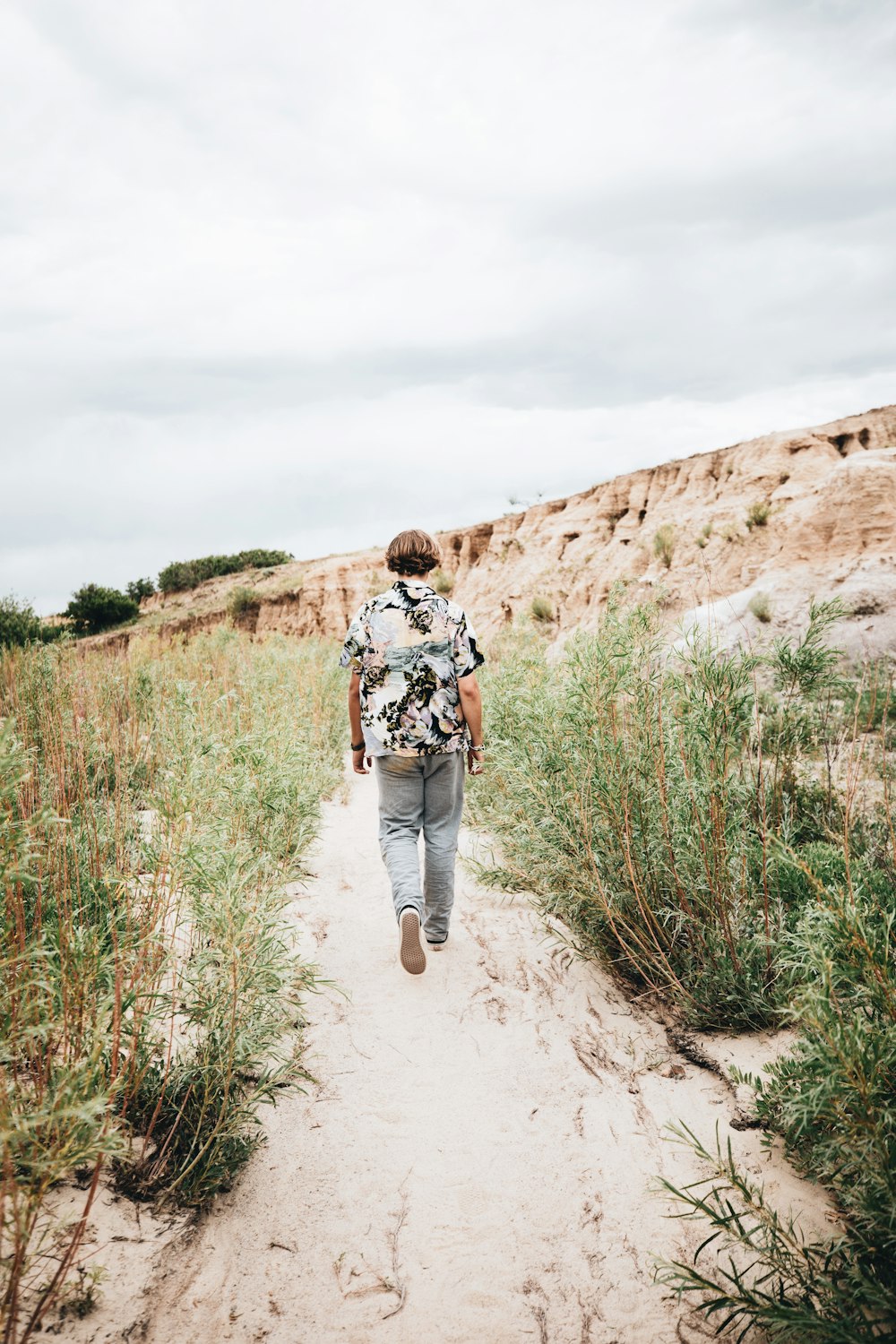 woman in black and white jacket walking on brown dirt road during daytime