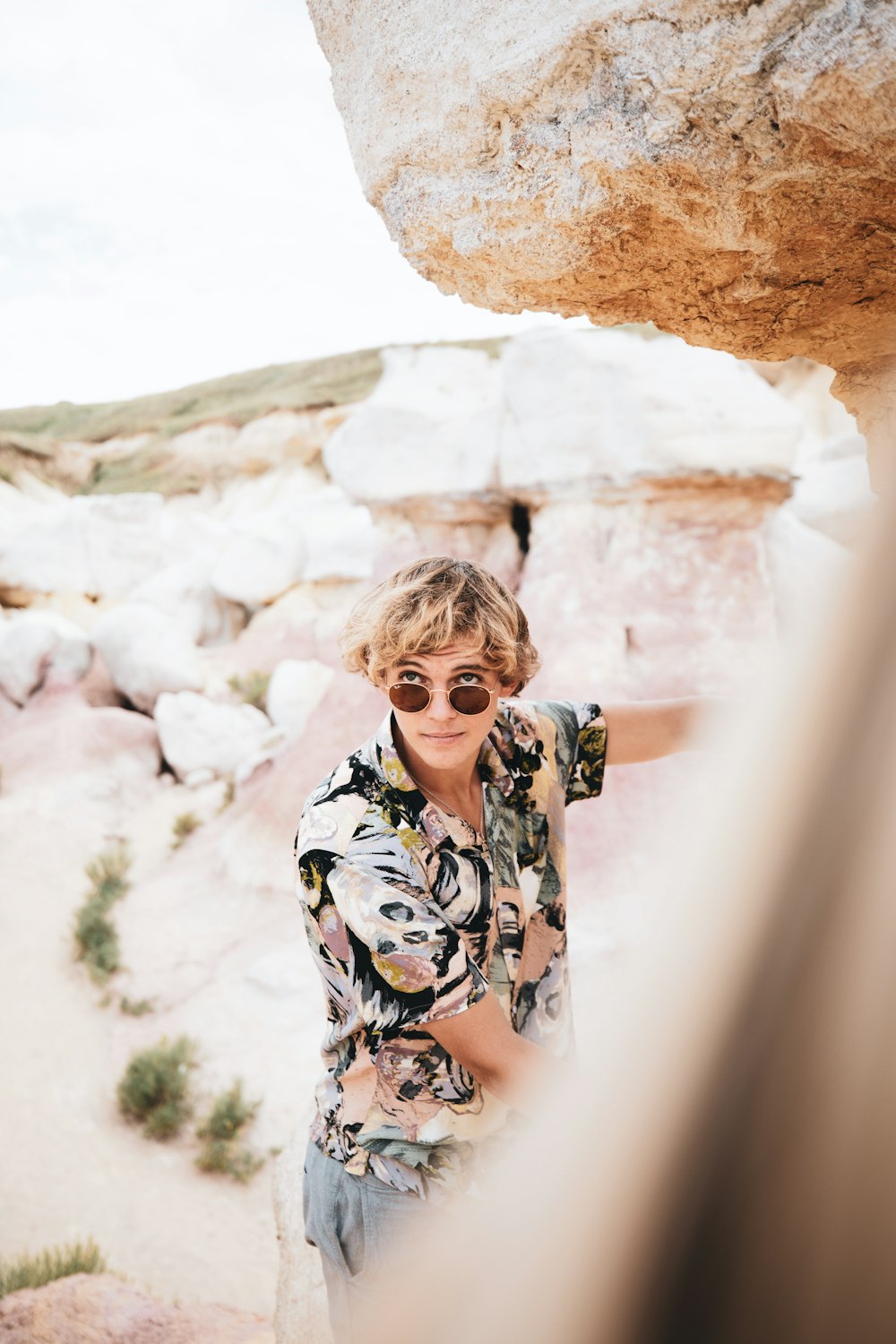 woman in black and white floral long sleeve shirt standing near brown rock