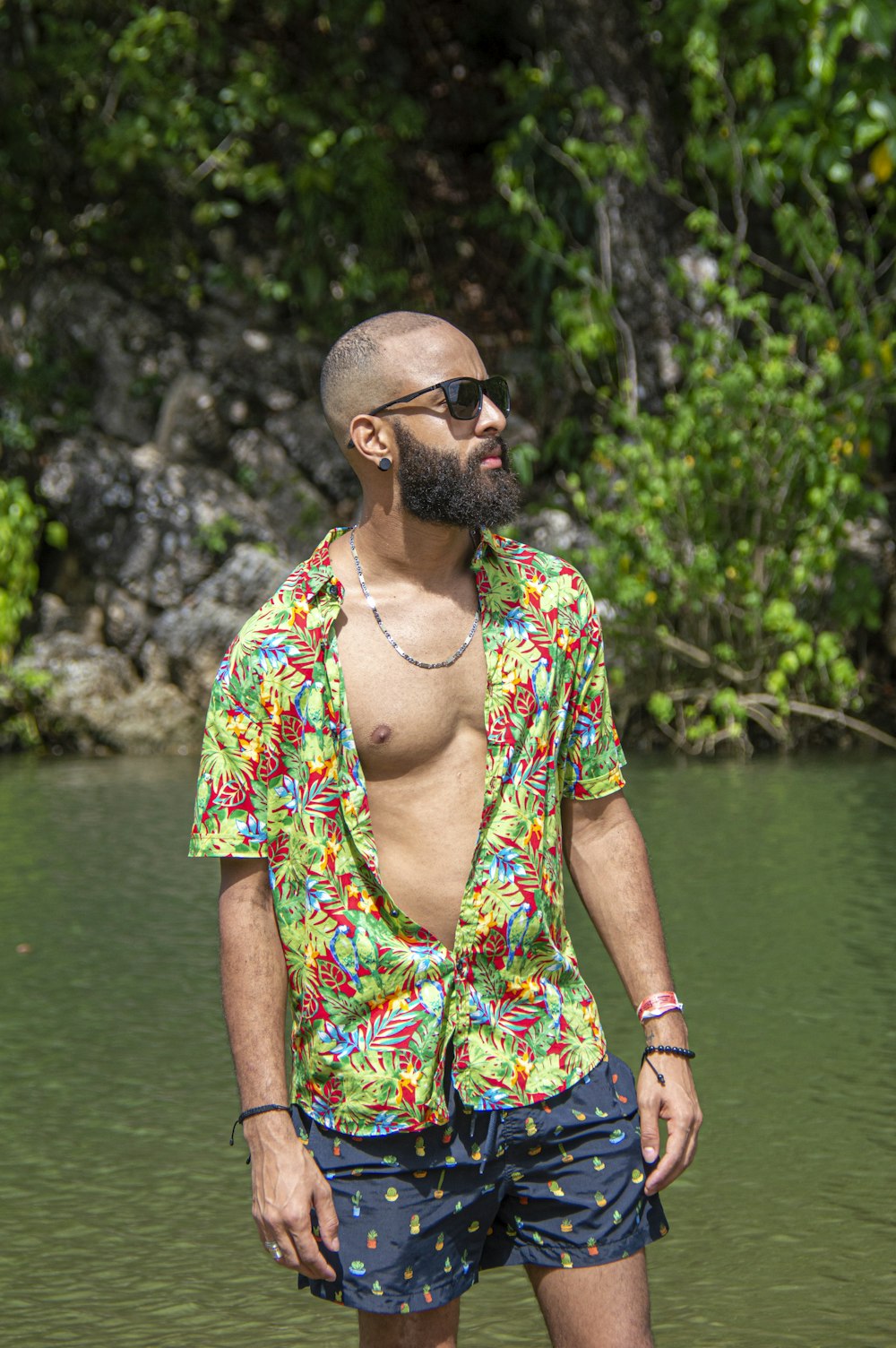 woman in green and yellow floral dress wearing black sunglasses standing near lake during daytime