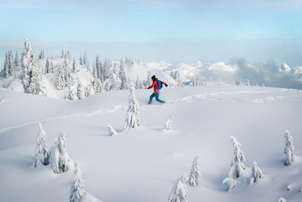 person in red jacket and black pants walking on snow covered ground during daytime