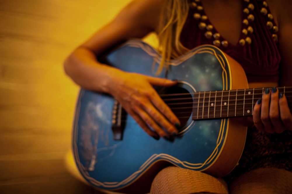 woman in yellow shirt playing blue acoustic guitar