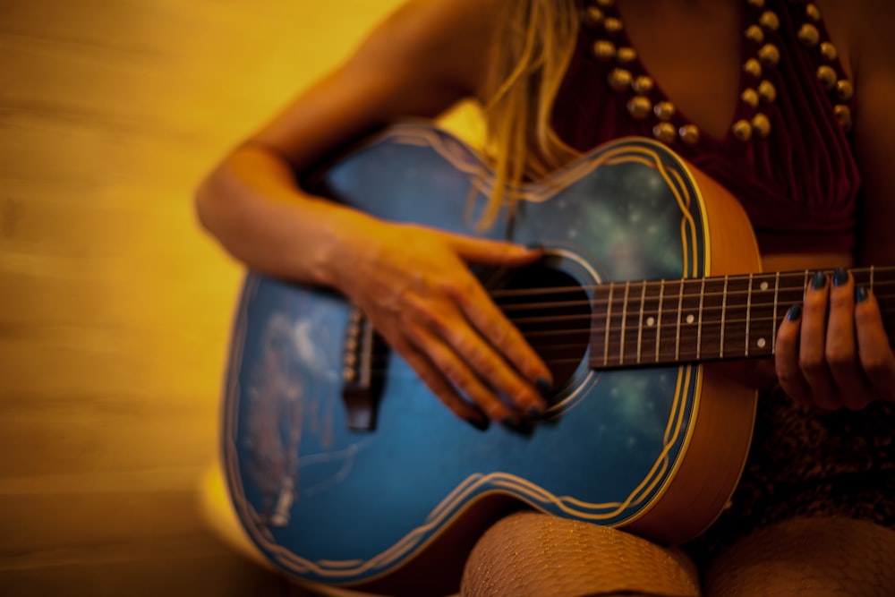 mulher na camisa amarela que joga a guitarra acústica azul